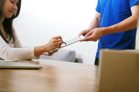 The recipient signs the receipt for the package. Fast box delivery service from the shipper for...