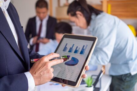 The financial advisor analyzes the operating income as a bar graph statistics in the tablet. Business people talking in meeting Business people work with the team.の写真素材