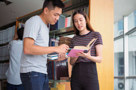 Two students study and read together in the library.の写真素材