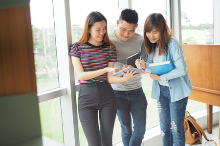 Student groups are viewing information in the tablet. Having a gesture of agreement and smiling,...