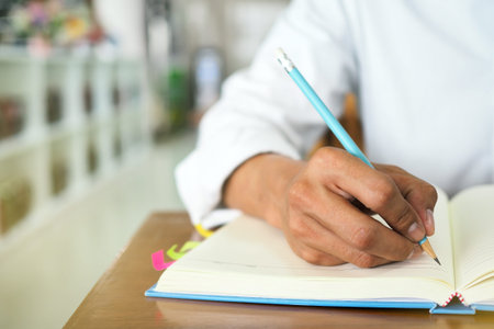 Men's hand is writing a book. Sit in the library