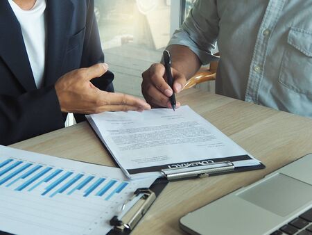 Business men are inviting and pointing at signing contracts. The contract is signed by the contractor to conduct business.の写真素材