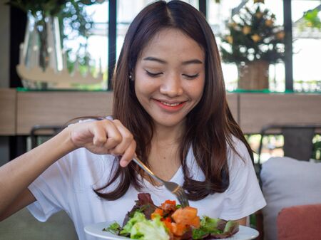 Asian women are happy to eat salmon salad. Food for good healthの写真素材