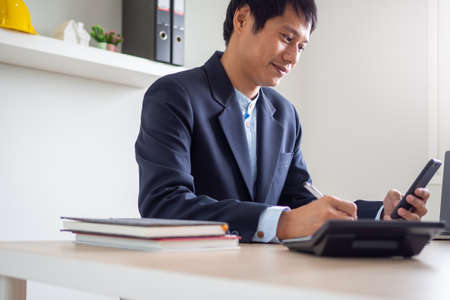 Young businessman are happy to see the investment index of company stocks rise via moblieの写真素材