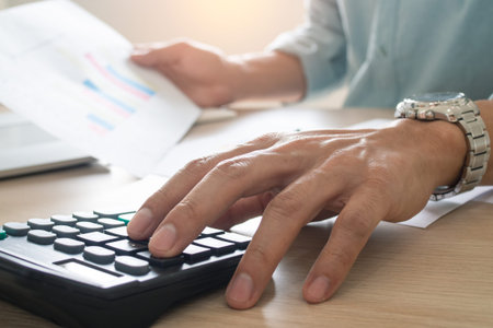 Businessmen sit and press the calculator to calculate and predict the company's power output...