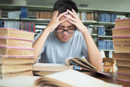 Students are stressed out with hard studying and reading in the library.の写真素材