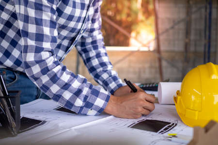 Close-up of the engineer's hand is drawing a plan on print with equipment, standing at desks and planning the construction of houses or apartments.の写真素材