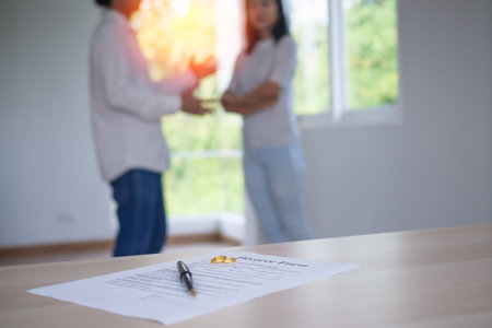 Close up of the documents of the divorce and the wedding ring placed on the table. couple are...