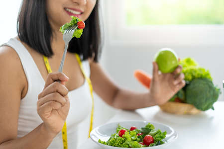 Women sitting eating fruit and vegetable salad with green apples. Women choosing healthy foods to feel happy. The concept of healthy eating and weight loss concepts.の写真素材