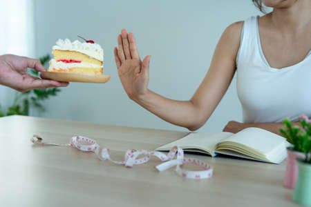 Woman refuse cake of friends. Woman's intention is not eat sweet and healthy weight control. Concept dietの写真素材