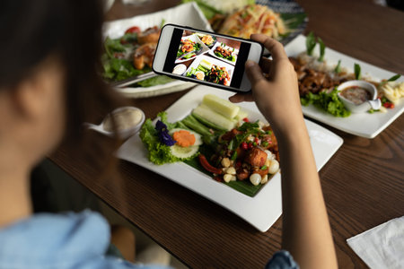 Woman taking pictures of a delicious lunch in a restaurant to pop upload in a social media. The...
