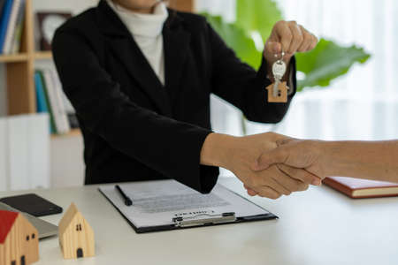 Sales representative shake hands and delivering the keys to the new homeownersの写真素材
