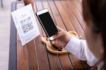 Close up of a woman's hand using a smartphone to scan a QR code to pay for food and drinks. Concept of scanning a QR code, using a mobile phone.の写真素材