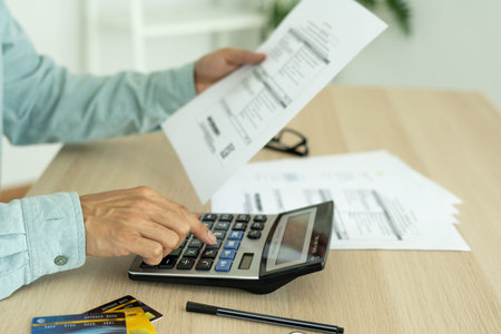 Man calculates the debt at hand with a calculator. Man is stressed and overthink by debt from many...