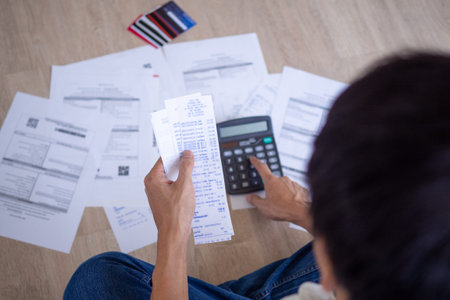 Businessman or butler is sitting at the press of various expense calculators on invoices and credit...