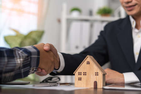 The real estate agent shakes hands with the client after agreeing to a contract for the sale of the home or insurance with legal effect. Success in house trading negotiations. Home or land mortgageの写真素材