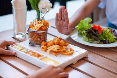 Young women reject fried foods and opt for a healthy salad. Women are losing weight by reducing fried foods, excess fat, dieting. good health, weight loss.の写真素材