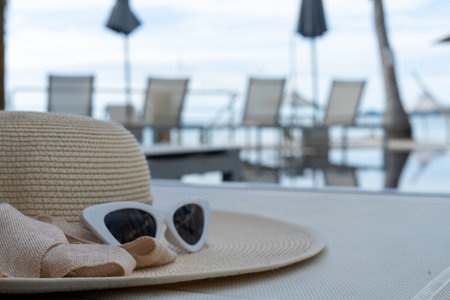hats and glasses on a pool table in the resort. Summer views and travel accessories, hats, sunglasses are ready for vacation trips.の写真素材