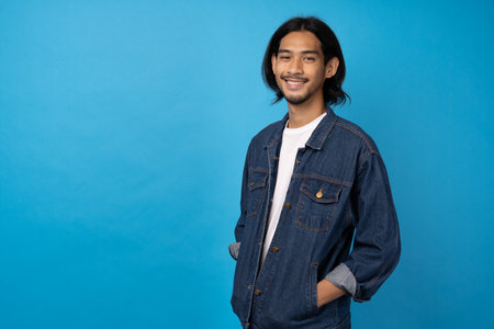 A long-haired young Asian man wearing a white T-shirt smile with a blue background. Asian man so cool and smartconceptの写真素材