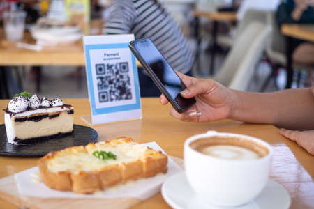 Women's hands are using  the phone to scan the qr code to select food menu. Scan to get discounts or pay for food. The concept of using a phone to transfer money or paying money online without cash.の写真素材