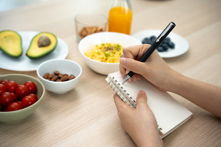 Diet, Dieting. women write keto plan for weight loss ,slim and good health. Female enjoy with correct nutrition, vegetables, almonds, avocados, tomatoes, salad. Nutritionist for healthyの写真素材