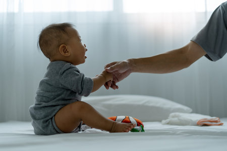 An Asian baby trusts his father's hand to stand up. father and son spending time together