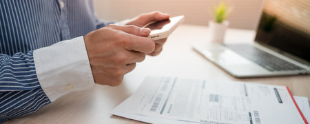 business man uses his phone to scan a barcode to pay his monthly credit card bill after receiving an invoice. online bill payment conceptの写真素材