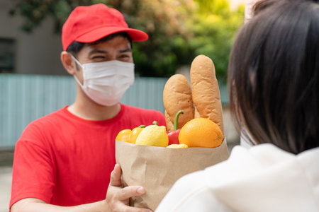 Food delivery staff wearing masks during the outbreak. Postman carry food bags to customers in front...