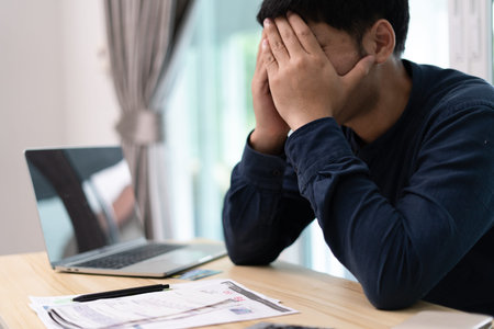 Asian man are worried about debt and expenses. Stressful person receive bank loan invoices. credit...