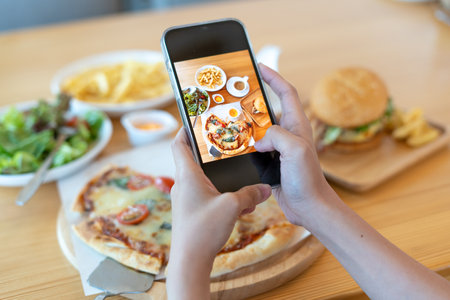 italian food. The restaurant owner takes a picture of the food on the table with a smartphone to post on a website. Online food delivery and ordering serviceの写真素材