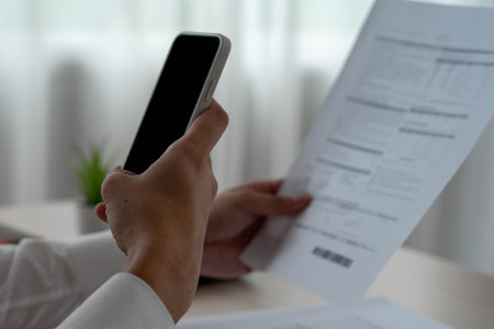 A business man uses his phone to scan a barcode to pay his monthly credit card bill after receiving...