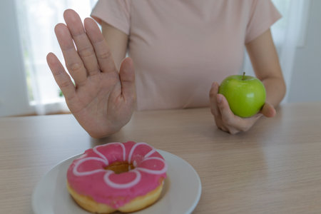Good health food and diet. Women reject junk food or unhealthy foods such as doughnuts and choose healthy foods such as green apple.の写真素材