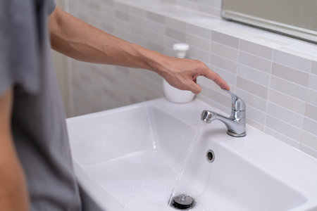 The faucet in the bathroom with running water. Man keeps turn off the water to save water energy and...