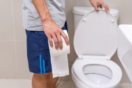 Man holding tissue paper stands in front of the toilet. Abdominal pain, appendicitis, colon cancer,...