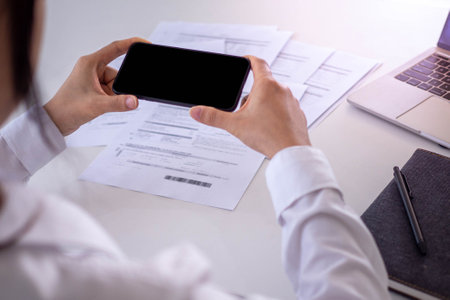 A business man uses his phone to scan a barcode to pay his monthly credit card bill after receiving an invoice. online bill payment conceptの写真素材