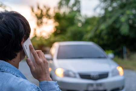 emergency safety. man is dialing a cell phone for an emergency number due to a car breakdown in the forest. Maintenance of the car before the trip increases safety from accidents.の写真素材