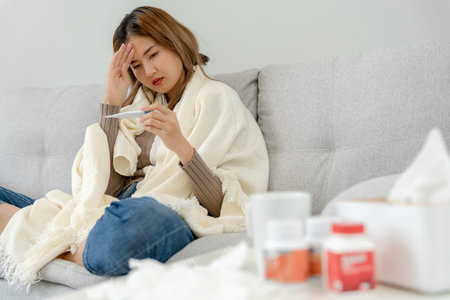 Young Asian woman having high fever while checking body temperature, female sneezing and runny nose...
