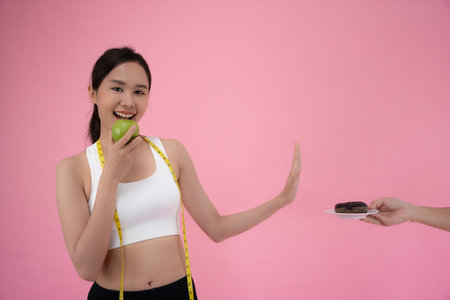 Diet and dieting. Beauty slim female body confuse donut. Woman in exercise clothes achieves weight loss goal for healthy life, crazy about thinness, thin waist, nutritionisの写真素材