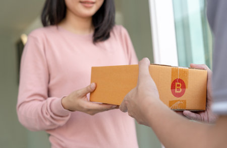 Happy smiling woman receives boxes parcel from courier in front house. Delivery man send deliver express. online shopping, paper containers, takeaway, postman, delivery service, packagesの写真素材