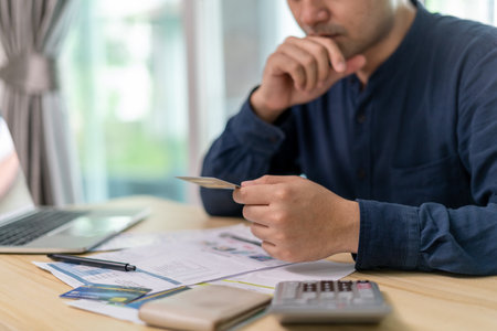 Stressed and headache asian man with large bills or invoices no money to pay to expenses and credit card debt. shortage, Financial problems, mortgage, loan, bankruptcy, bankrupt, poor, empty walletの写真素材
