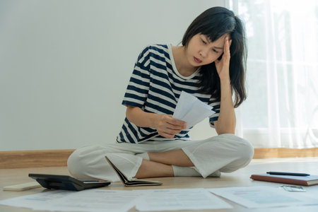 Stressed and headache asian woman with large bills or invoices no money to pay to expenses and credit card debt. shortage, Financial problems, mortgage, loan, bankruptcy, bankrupt, poor, empty walletの写真素材