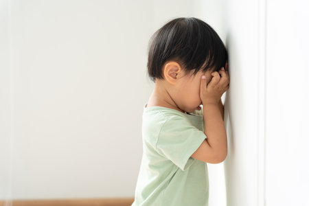 little asian children kid girl covering his eyes with hands, playing hide and seek standing next a wall house, Adorable child having fun in the home. happy family have fun with kids, activity, learningの写真素材