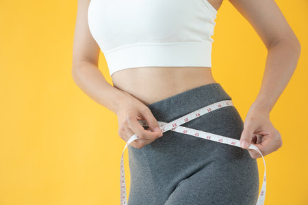 Diet and dieting. Beauty slim female body use tape measure. Woman in exercise clothes achieves weight loss goal for healthy life, crazy about thinness, thin waist, nutritionist.の写真素材