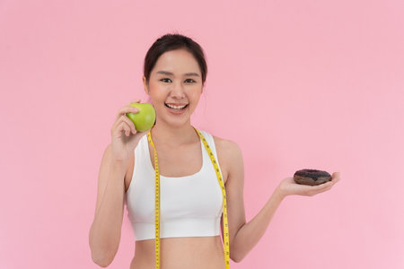 slim body Women choose during green apple and chocolate donut, female choose green apple for diet. Good healthy food. weight lose, balance, control, reduce fat, low calories, routines, exercise.の写真素材