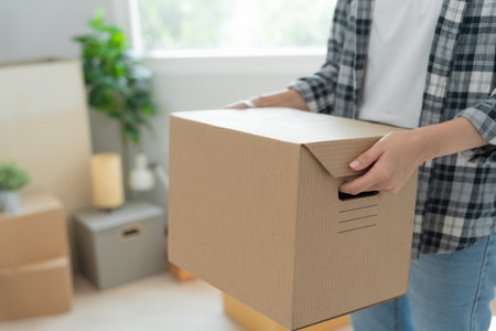Moving house, relocation. Woman hand holding carton box on new apartment, inside the room was a cardboard box containing personal belongings and furniture. move in the house or condominiumの写真素材