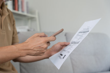 business man use phone to scan barcode or QR codes to pay credit card bill after receiving document invoice online. payment, receive, paying electricity, digital payments without money, technologyの写真素材