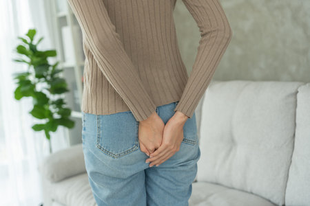 Girl hand holding her bottom because having abdominal pain and hemorrhoids, health care,...