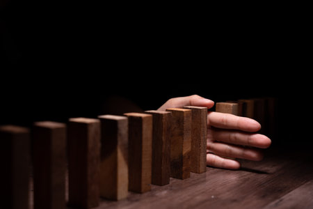 insurance with hands protect domino. Businessman hands stop dominoes falling in business crisis. business risk control and planning and strategies to run prevent insurance businesses.の写真素材