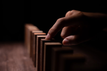 insurance with hands protect domino. Businessman hands stop dominoes falling in business crisis. business risk control and planning and strategies to run prevent insurance businesses.の写真素材