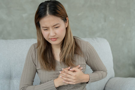 hand hold chest with heart attack symptoms, asian woman have chest pain caused by heart disease,...